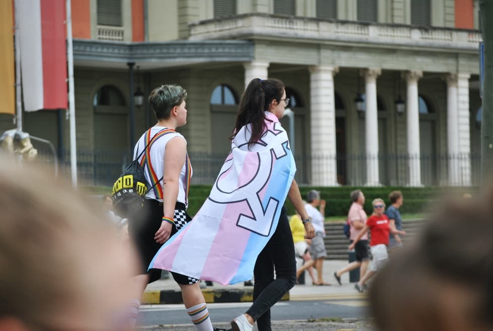 Pessoa vestindo a bandeira trans como uma capa.